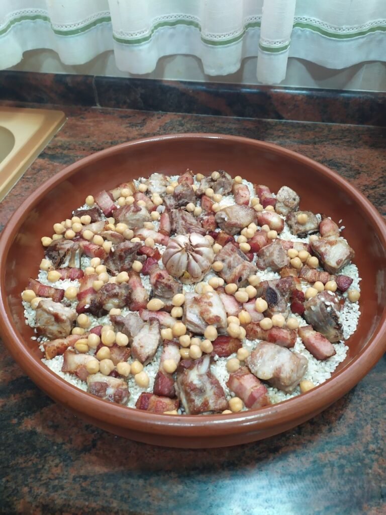 Cazuela de barro con arroz, cabeza de ajos, panceta, costilla de cerdo y garbanzos (arroz al horno)