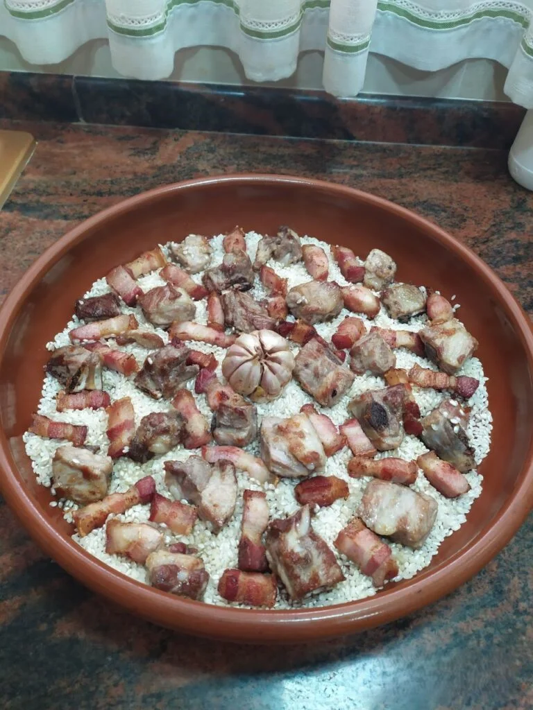 Cazuela de barro con arroz, cabeza de ajos, panceta y costilla de cerdo (arroz al horno)
